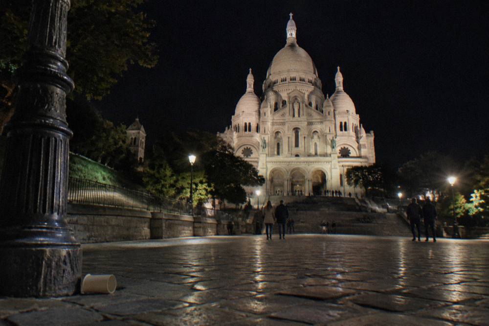Sacre-Coeur basilica lit against a dark sky above the rooftops of Montmartre