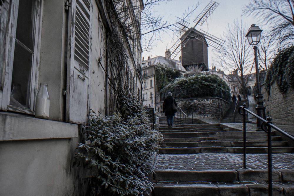 Narrow cobbled street with stairs climbing between old Montmartre buildings