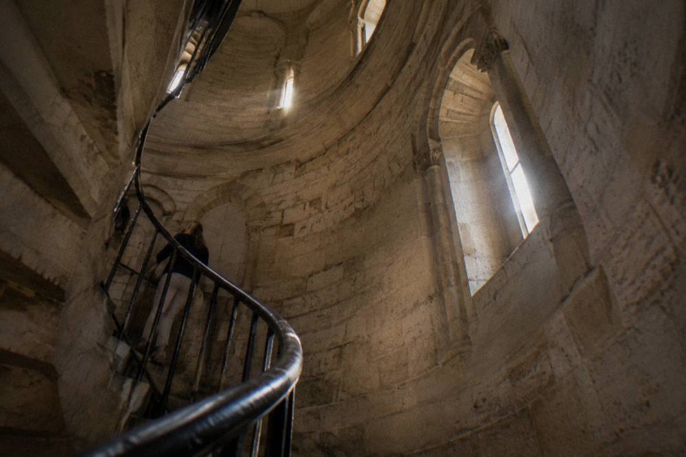 A narrow spiral staircase inside the Sacre-Coeur dome lit by small windows