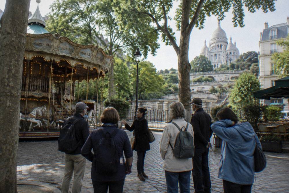 A guided walking group gathered on a cobbled Montmartre street below the basilica