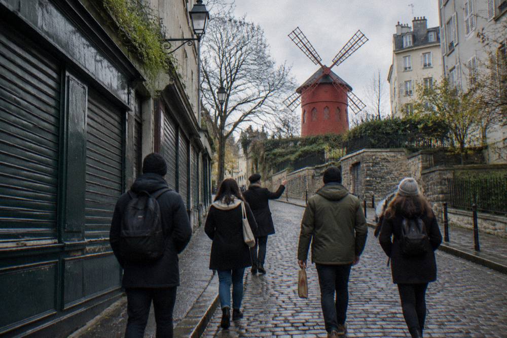 A guide leading a small group along a shop-lined Montmartre street