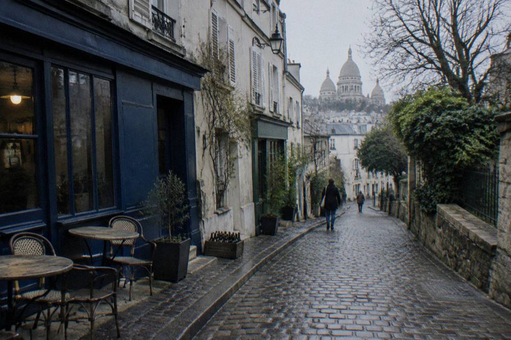 Narrow cobbled street of Montmartre lined with small shops and cafés in morning light