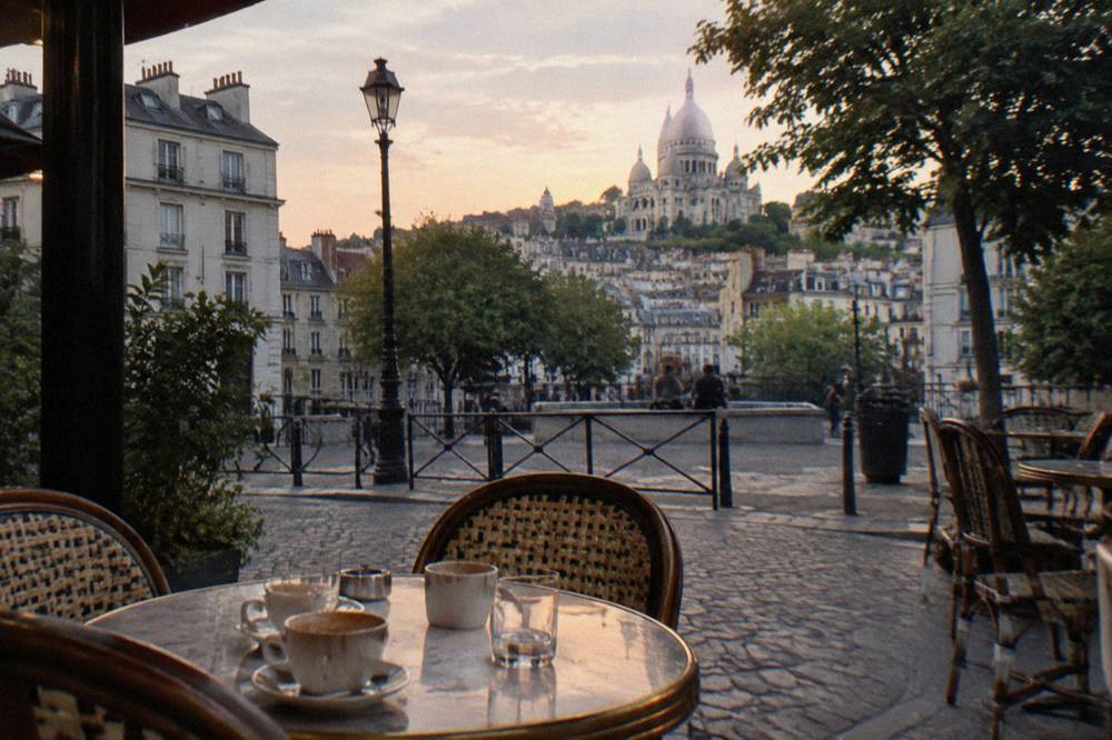 Café terrace on a Montmartre street corner with the white basilica rising behind rooftops