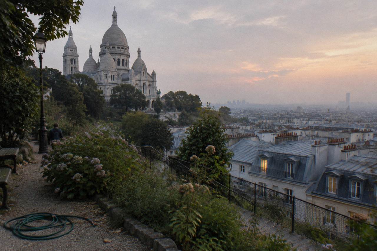 View across Paris rooftops from the hillside below the white domed basilica of Montmartre