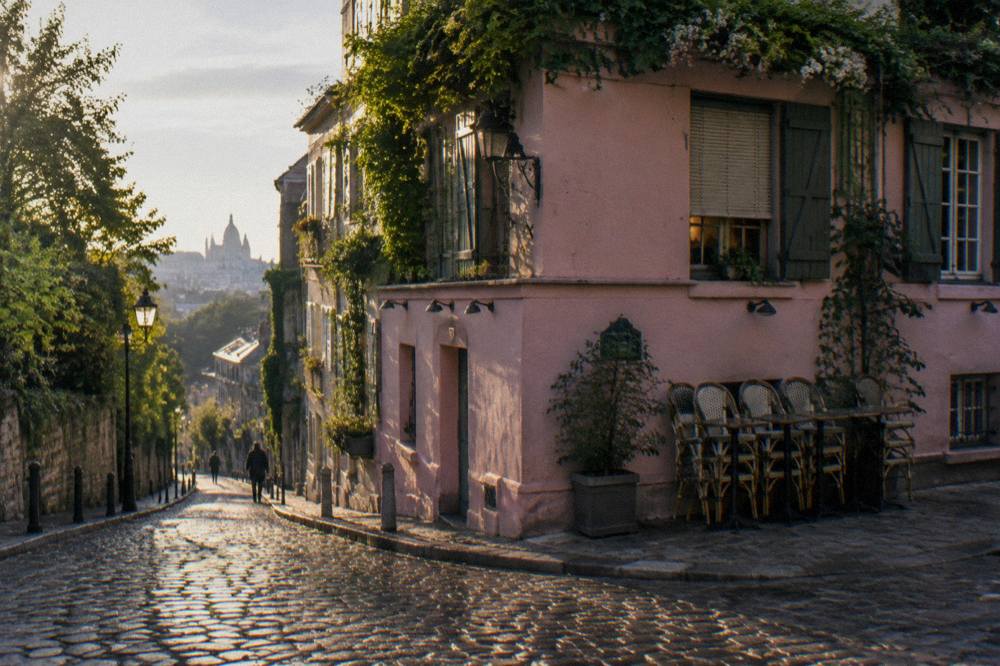 Empty cobblestone street in Montmartre with cafe tables in morning light