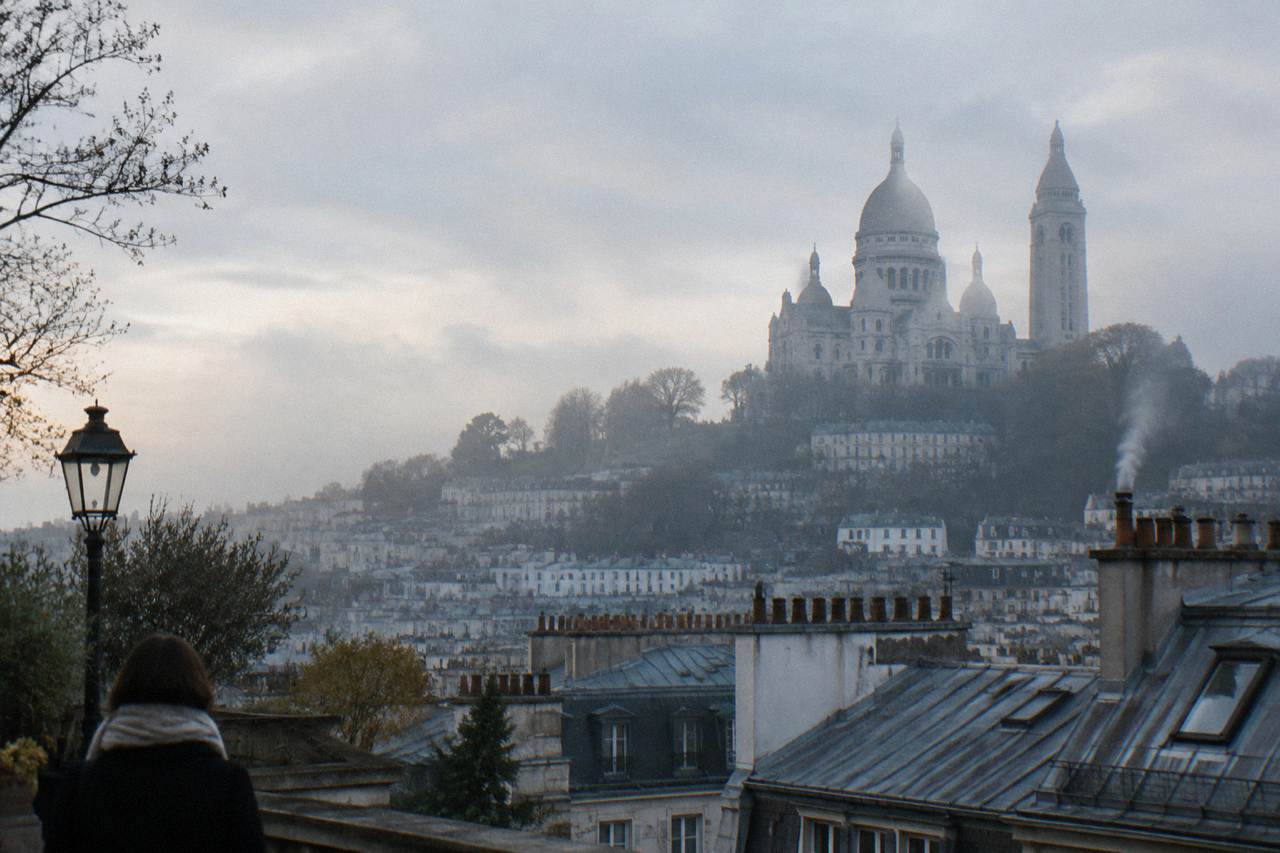 View over Montmartre rooftops toward Sacre-Coeur basilica in soft light