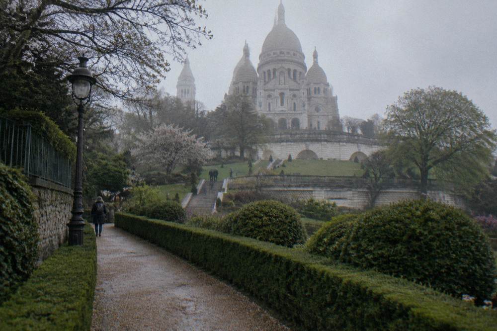 Terraced gardens below the Sacre-Coeur basilica with gravel paths and green shrubs on the hillside
