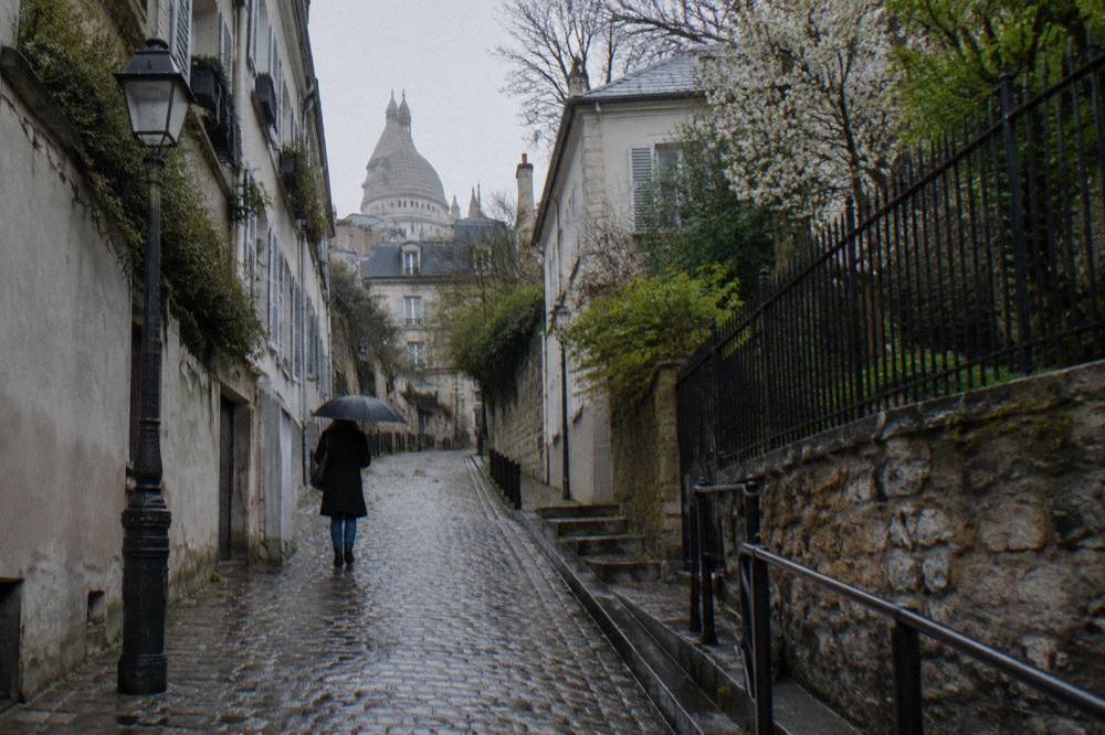 Cobbled lane in Montmartre climbing between tall buildings with iron railings