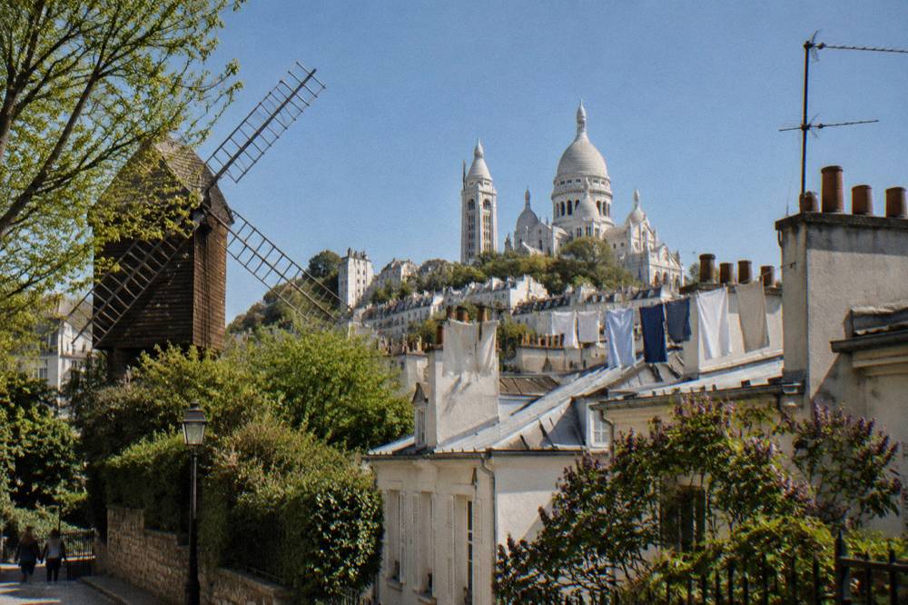 White domes of Sacre-Coeur basilica rising above Montmartre rooftops under a clear sky