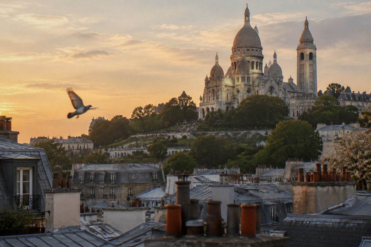 View over Montmartre rooftops toward Sacre-Coeur basilica in late afternoon light