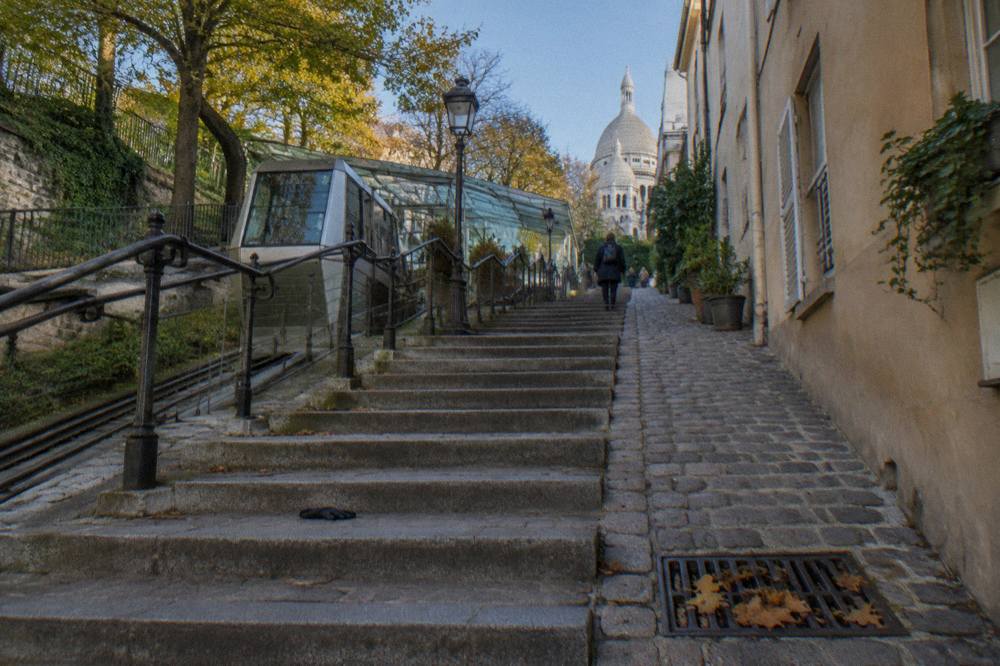 Worn cobblestone lane in Montmartre with stone steps rising between old apartment walls