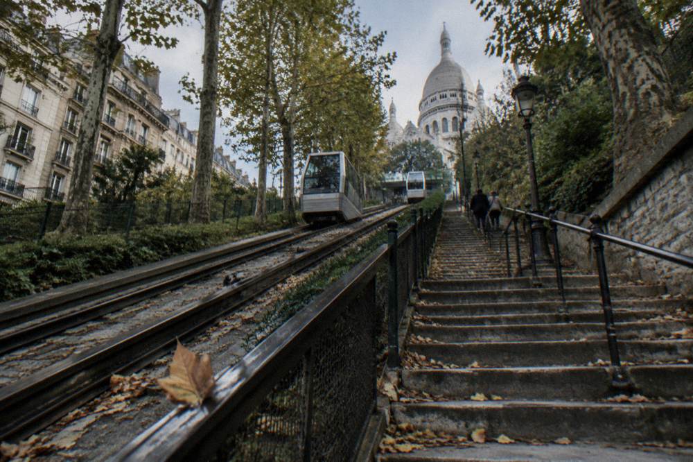 Stone staircase beside a funicular track climbing the leafy flank below the basilica