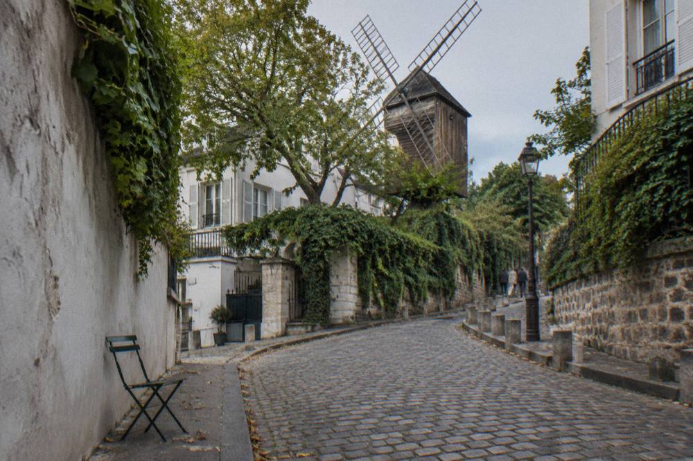 Narrow cobbled lane in Montmartre lined with small cafes and ivy-covered walls