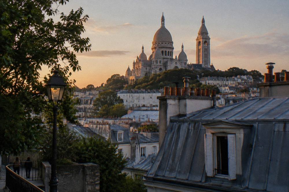 The domes and bell tower of the white basilica rising above the rooftops of Montmartre