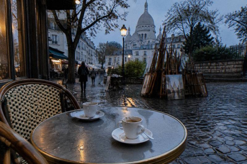 A private guide talking with two visitors at a quiet Montmartre viewpoint overlooking Paris, illustrating private guided tours of the hill's art, food and Sacre-Coeur landmarks at your own pace.