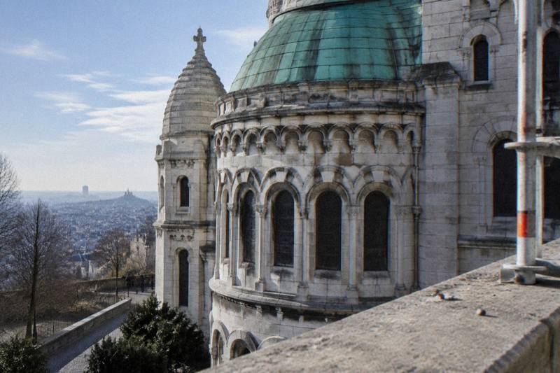 Sacre-Coeur Basilica's pale stone facade and dome seen from the steps on Montmartre hill, a stop on guided tours that also cover the surrounding streets and views over Paris.