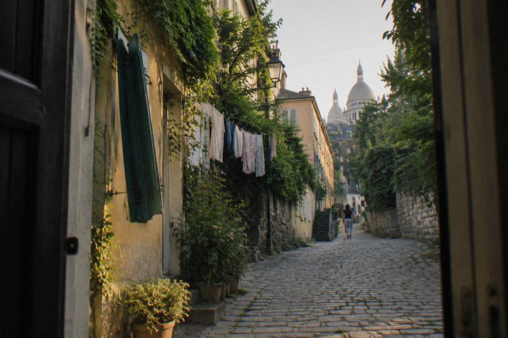 Narrow cobbled street in Montmartre with ivy-covered houses climbing the hill