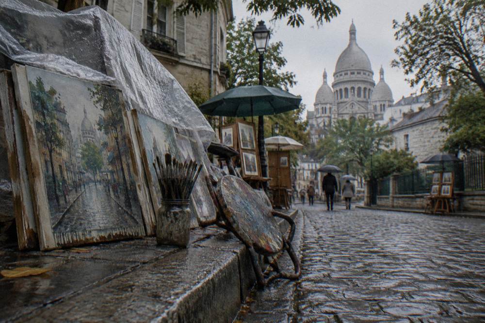 Street artist's stall and painted canvases along a Montmartre lane
