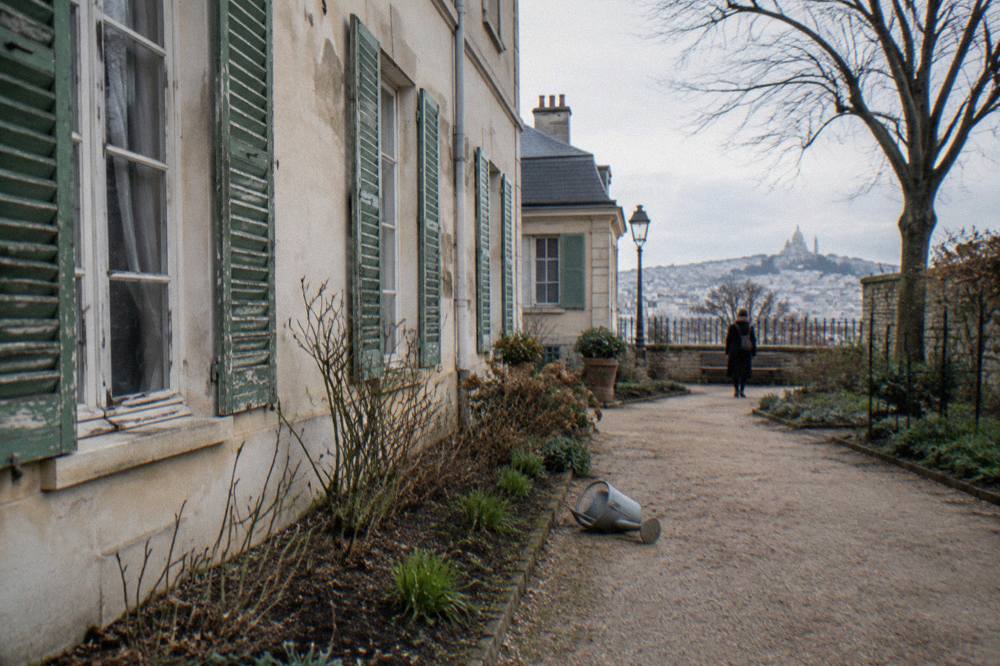 A 17th-century house facade with green shutters and a small garden in Montmartre