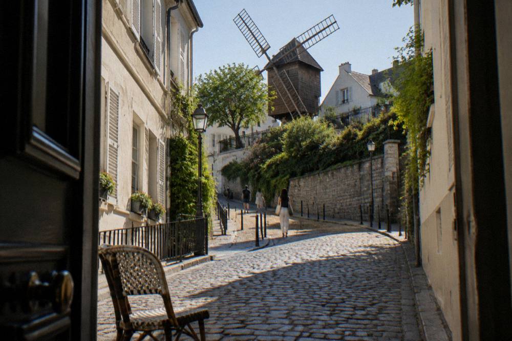 Narrow cobbled street climbing between small houses toward the top of Montmartre