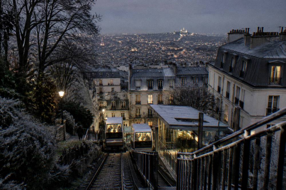 The illuminated city skyline spread out below the dark silhouette of Montmartre rooftops