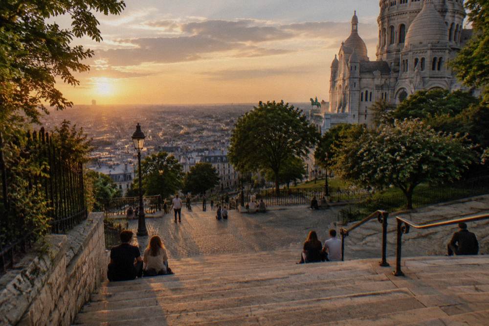 The long stone staircase rising toward the Sacre-Coeur basilica with people resting on the steps