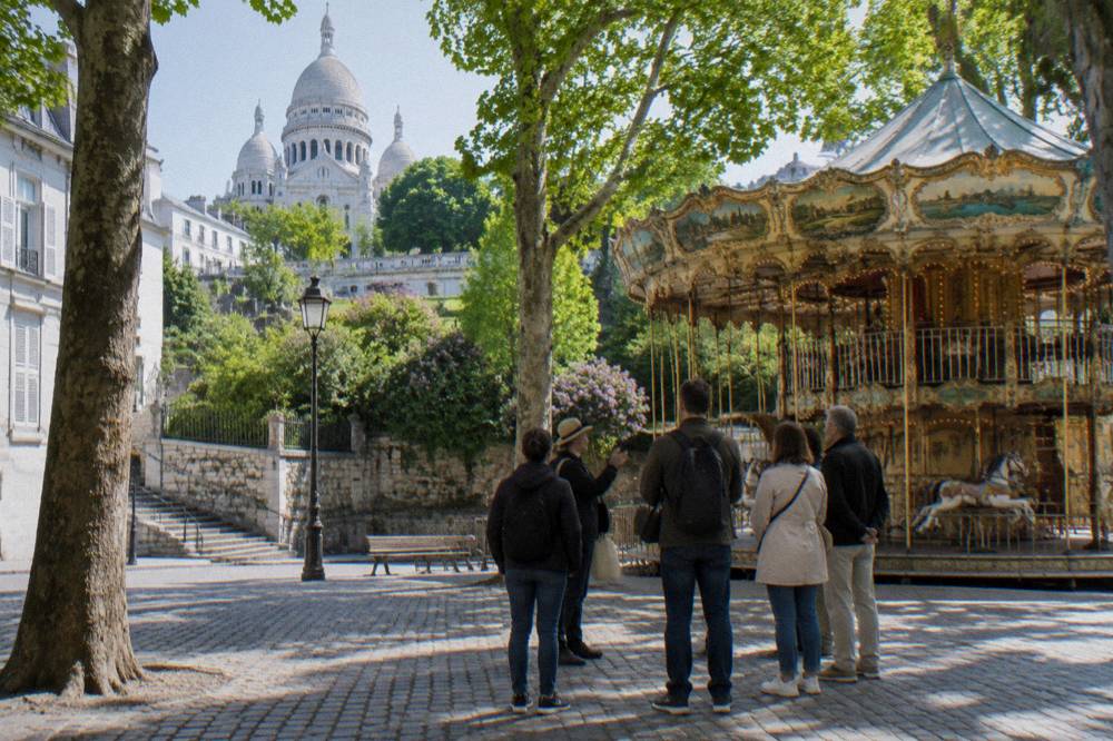 A small group gathered with a guide at the foot of the Montmartre hill before beginning the walk upward