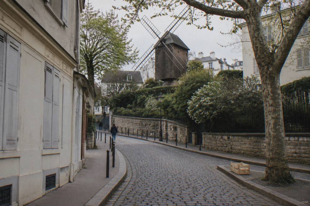 Narrow Montmartre street curving uphill past shuttered shopfronts