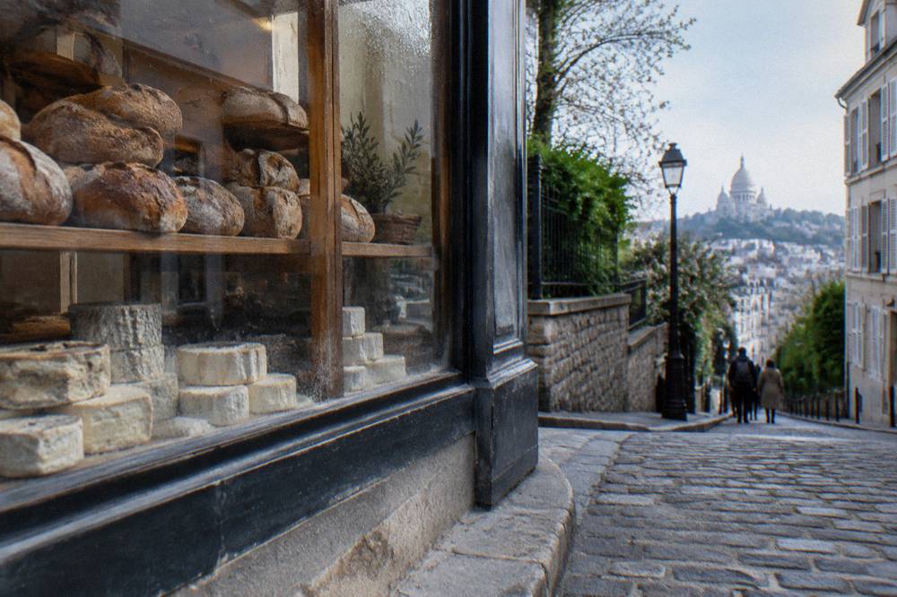 Cheese and pastry shop window with fresh breads on wooden shelves