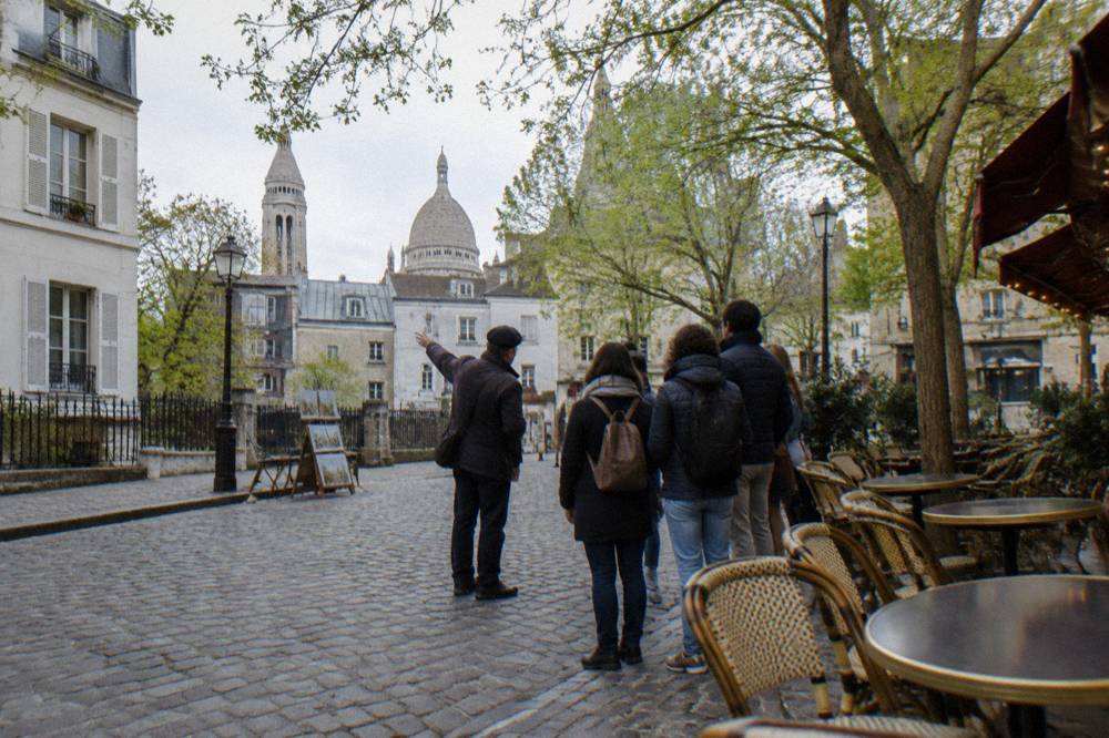 Guide speaking to a small cluster of visitors on a Montmartre street corner