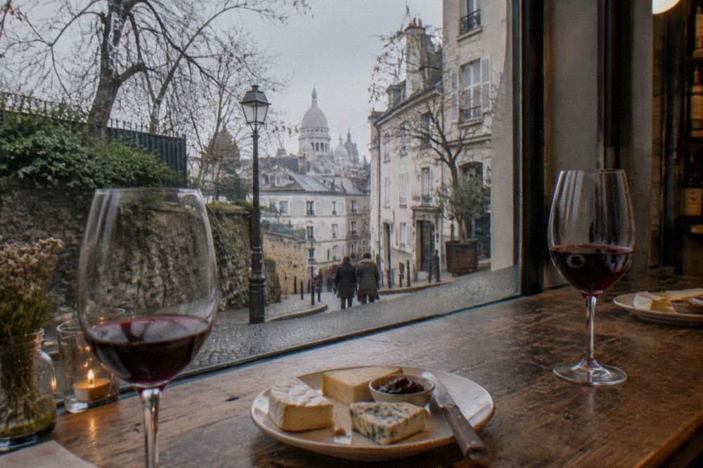 A table with glasses of red wine and plates of cheese in a small Parisian shop