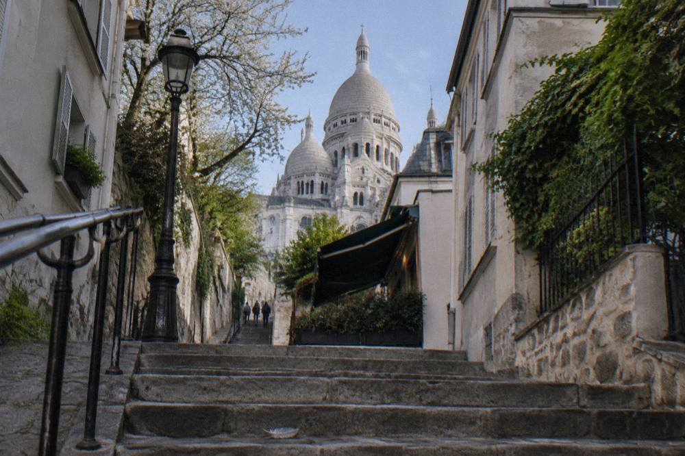 A narrow cobbled Paris street climbing toward a white domed church on a hill