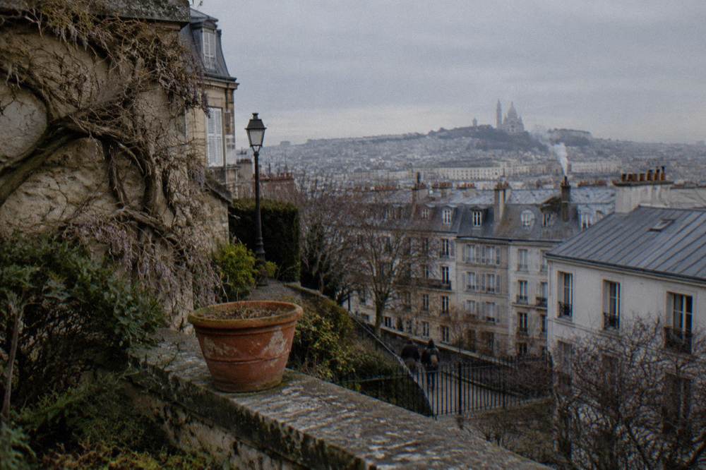 A view over Paris rooftops from a hilltop terrace in late afternoon light