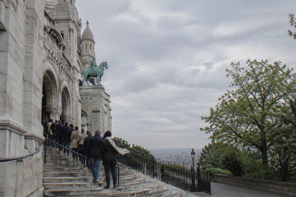 Visitors in modest clothing walking up the stone steps toward the basilica entrance