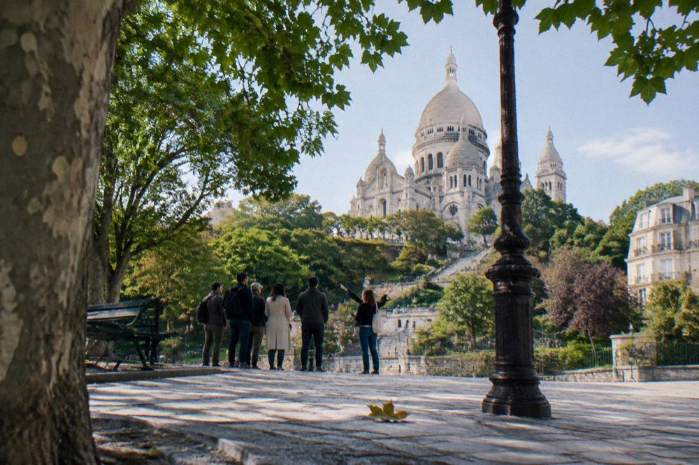 Tour guide speaking to a small group on a Montmartre street with the basilica in the background