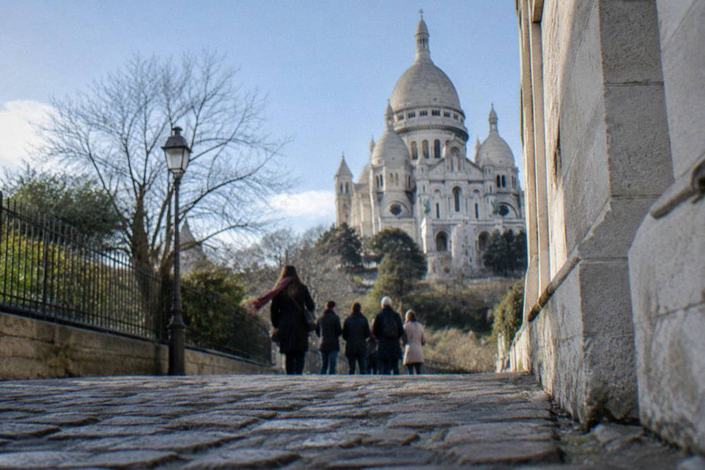 Small walking tour group gathered on a cobbled Montmartre street near the basilica
